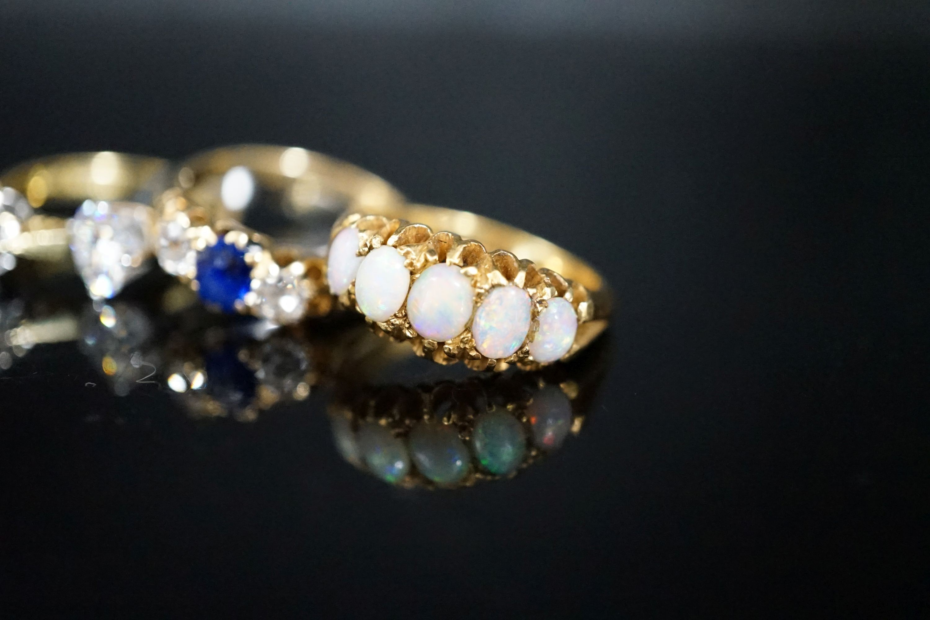 Two modern solitaire moissanite? rings (one set in 18ct gold, one in platinum), an 18ct & plat, sapphire and diamond set three stone ring, size Q and a yellow metal (stamped 18) and graduated five stone white opal set ha